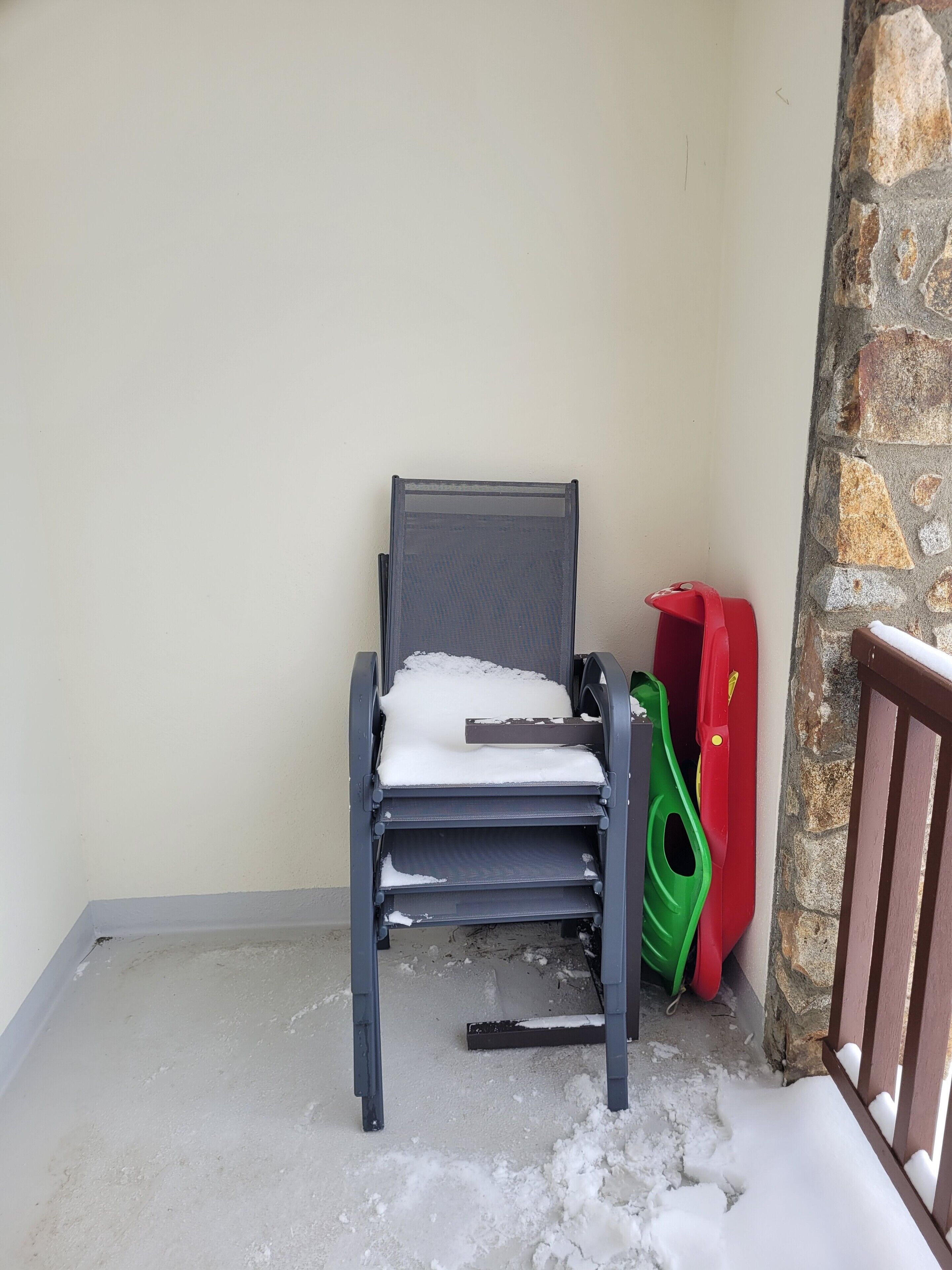 A chair with a white cushion and a metal frame, positioned against a wall with a stone texture.