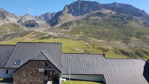 A mountain lodge with a stone facade and a metal roof, set against a backdrop of rugged mountains. - La Mongie 2 rooms 4 persons Residence Pic du Midi parking and swimming pool (Bagnères-De-Bigorre)
