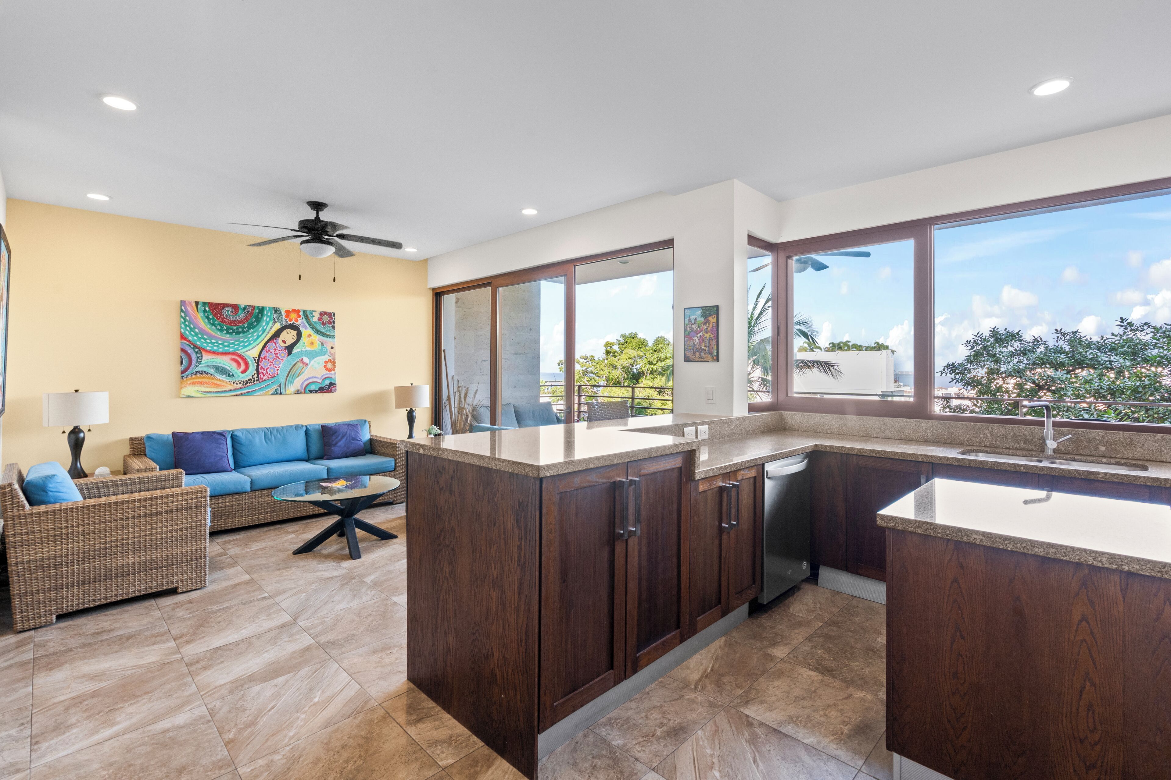 A modern kitchen with dark wood cabinets, a large island, and a view of the outdoors.