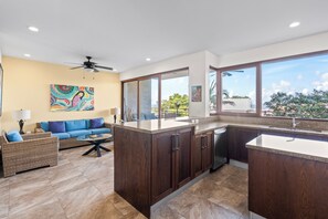 A modern kitchen with dark wood cabinets, a large island, and a view of the outdoors. - Residences by Pinnacle, Rooftop Pool & Bar, Zona Romantica, Puerto Vallarta (Puerto Vallarta)