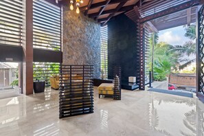 Un interior moderno con una pared de piedra, una zona de estar con sofá y sillones, y vistas al exterior.
