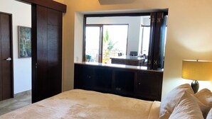 Habitación de hotel con cama, escritorio con computadora, espejo y ventana con vista al exterior.