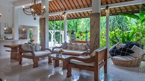 A spacious living area with wooden furniture, a ceiling fan, and a view of lush greenery. - Bright and Quiet Villa for 6 people. Close to Shops in Seminyak (Seminyak)