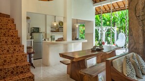 A spacious kitchen with a central island, a dining area with a wooden table and bench, and a staircase with patterned tiles. - Bright and Quiet Villa for 6 people. Close to Shops in Seminyak (Seminyak)