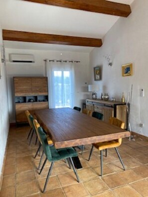 Un comedor con una larga mesa de madera y sillas tapizadas en verde.