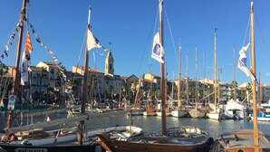 Un puerto deportivo con varias embarcaciones amarradas, cielo despejado y edificios al fondo.