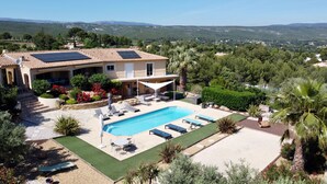 Una villa con piscina, mobiliario exterior y paneles solares.