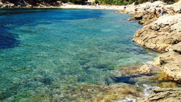 Una zona costera despejada con costas rocosas y una playa arenosa.