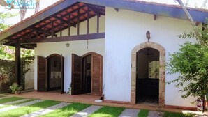 Un edificio con un porche cubierto, un arco de piedra y un pequeño jardín con un sendero de piedra.