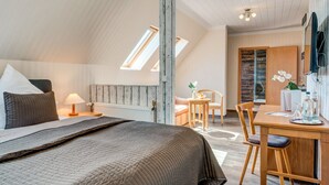 Un dormitorio con una cama grande, un escritorio de madera y una silla. Se ve una ventana con vistas al exterior.