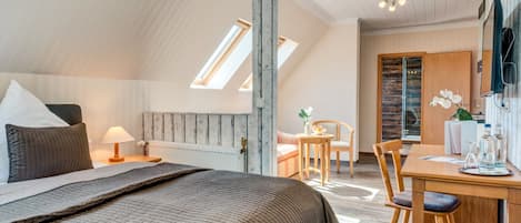 Un dormitorio con una cama grande, un escritorio de madera y una silla. Se ve una ventana con vistas al exterior.