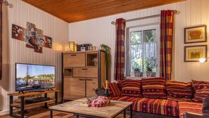 Een gezellige woonkamer met een houten tv-meubel, een bank met gekleurde kussens en een houten salontafel.