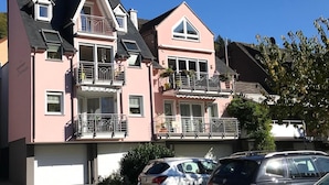 Un edificio a due piani con facciata rosa, diversi balconi e un garage.