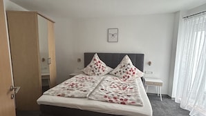 Una camera d'albergo con un letto, un armadio, un comodino e una finestra con tende.