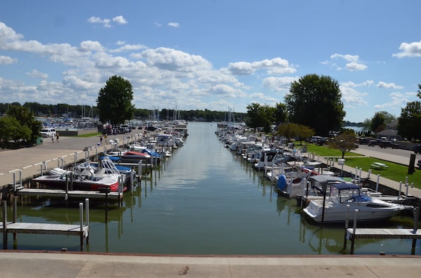 A marina with boats docked along a calm waterway, surrounded by greenery and a clear sky.