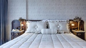 A neatly made bed with a quilted cover, two bedside tables with lamps, and a patterned wall. - The Rhinos 6 (Guildford)