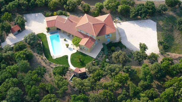 Une vue aérienne d’une grande maison avec une piscine, entourée d’arbres et d’une pelouse bien entretenue.