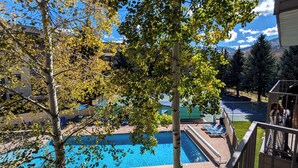 Une piscine entourée d’arbres, avec une vue sur les montagnes en arrière-plan.