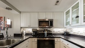 A modern kitchen with white cabinetry, stainless steel appliances, and a black countertop. - 2BR/2BA Remodeled-All Rooms are Oceanfront! 12th Floor-2 Balconies-Beach Locker! (Myrtle Beach)