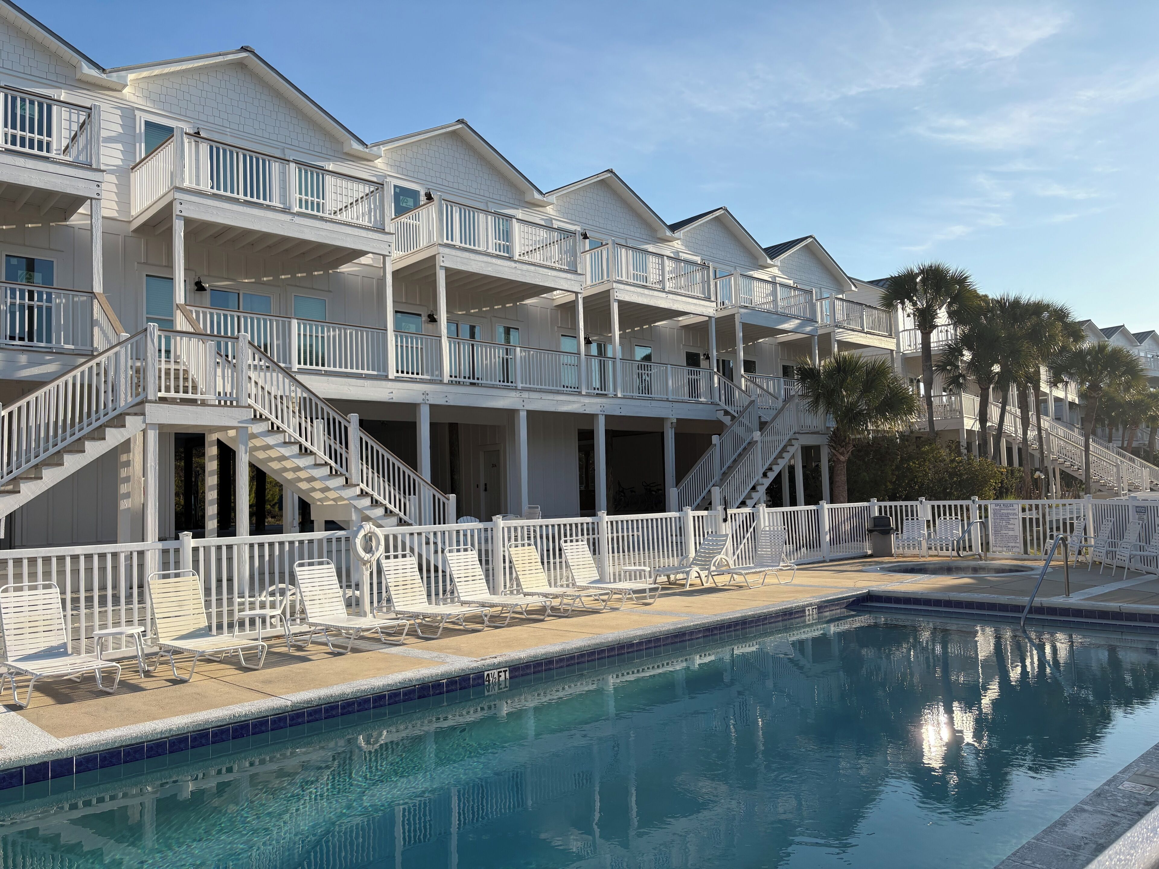 A multi-story hotel with balconies, a swimming pool, and palm trees.