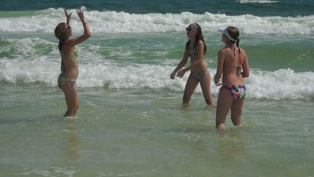 Three people playing beach volleyball in the ocean.