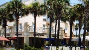 A hotel with a sign reading "ULFPLAC" surrounded by palm trees and a patio area.