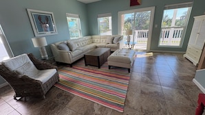 A living room with a sectional sofa, a chair, a coffee table, a colorful rug, and a ceiling fan.