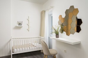 A white crib with a beige chair, a white shelf with a plant, and a hexagonal mirror on the wall. - Ideal for a family vacation. Heated pool. Local breakfast optional available (Svetvincenat)