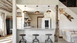 A kitchen with a white island, three stools, hanging pendant lights, and a sign indicating a hotel delivery entrance. - ★ Seen in 250 Articles ★ 1min → Town ★ Private ★ Great Kitchen ★ Luxury Home ★ (Round Top)