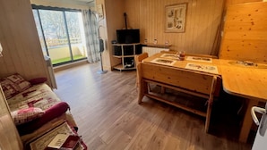 A cozy living room with a wooden bench, a television, and a dining table with placemats. - T2 mountain atmosphere (Villard-De-Lans)