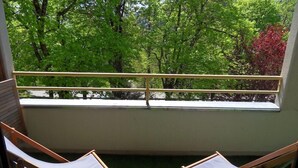 A balcony with two wooden lounge chairs and a view of green trees. - T2 mountain atmosphere (Villard-De-Lans)