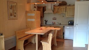 A kitchen with wooden cabinets, a white stove, and a dining table with benches. - T2 mountain atmosphere (Villard-De-Lans)