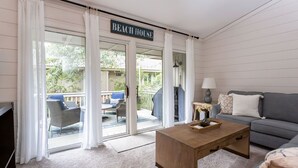 Ein Interieur eines Strandhauses mit einer Couch, einem Couchtisch und einem Schild mit der Aufschrift 'BEACH HOUSE' über dem Eingang.