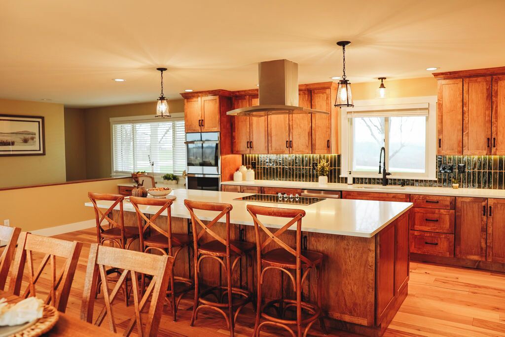 Une cuisine spacieuse avec des meubles en bois, un grand îlot central doté de tabourets et une cuisinière moderne.