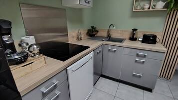 A modern kitchen with a black stove, white dishwasher, and grey cabinets.