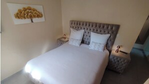 A neatly made bed with a tufted headboard, two bedside tables, and a wall-mounted artwork. - 50m2 of silence in the heart of Vitrolles (Vitrolles)
