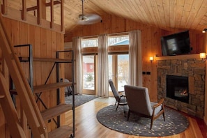 Un int érieur en bois avec une cheminée, un téléviseur et un fauteuil.