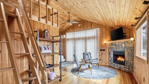 Un interior de madera con chimenea, un televisor y una alfombra circular.