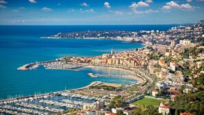 Un paysage urbain côtier avec un port de plaisance, des bâtiments et une vue dégagée sur la mer.