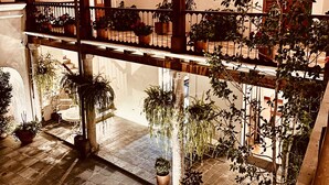 A covered outdoor area with multiple levels, potted plants, and a tiled floor.