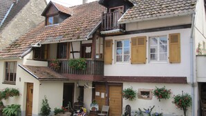 Ein traditionelles Haus im europäischen Stil mit einem Balkon, hölzernen Fensterläden und Blumentöpfen.