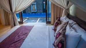 Een bed met een wit en paars dekbed, een houten hoofdbord en twee kussens met roze details.