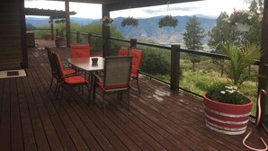 A wooden deck with a table and chairs, overlooking a mountainous landscape. - Stunning Post and Beam Home with the best views in the valley, wheelchair acc. (Penticton)