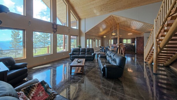 A spacious living area with large windows, a high ceiling, and a wooden staircase. - Stunning Post and Beam Home with the best views in the valley, wheelchair acc. (Penticton)