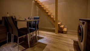 A compact kitchen with a wooden staircase, a dining area with modern chairs, and a washing machine. - Fully privatized apartment with jacuzzi and steam shower (Colmar)