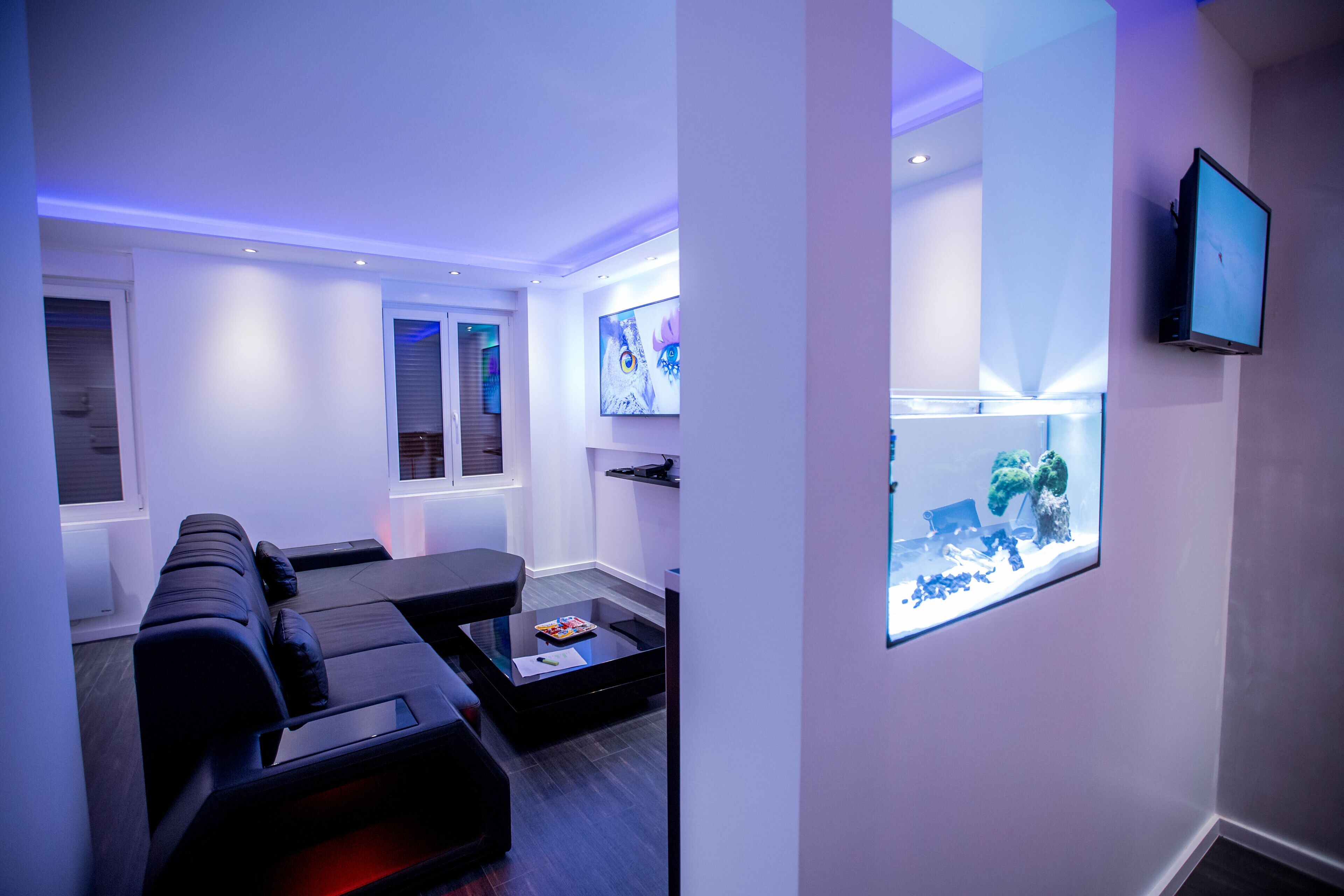 Een moderne woonkamer met een hoekbank, een salontafel en een flatscreen televisie aan de muur.