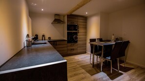 A modern kitchen with a wooden countertop, built-in oven, and dining area with chairs. - Fully privatized apartment with jacuzzi and steam shower (Colmar)