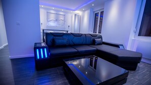 A modern living room with a sectional sofa, a glass coffee table, and ambient lighting. - Fully privatized apartment with jacuzzi and steam shower (Colmar)