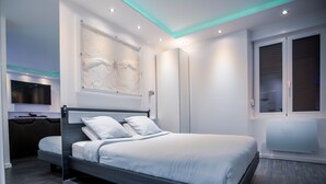 A modern hotel room with a bed, a TV, and a large window. - Fully privatized apartment with jacuzzi and steam shower (Colmar)