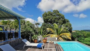 Una terraza de madera con sillones de descanso y una piscina.